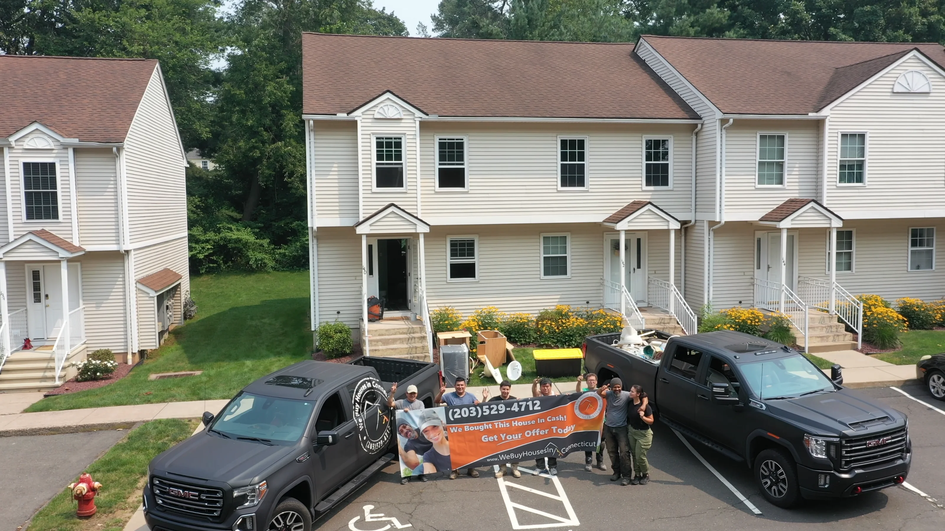 Jerryll Noorden and his crew with their two We Buy Houses In Connecticut trucks in front of a Connecticut house they bought for cash